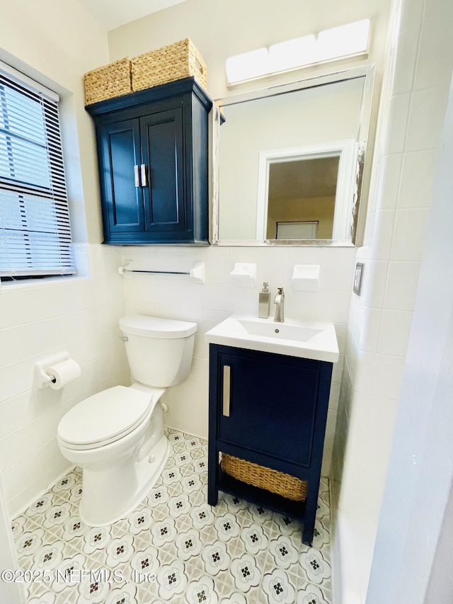 bathroom featuring tile patterned flooring, tile walls, toilet, and vanity