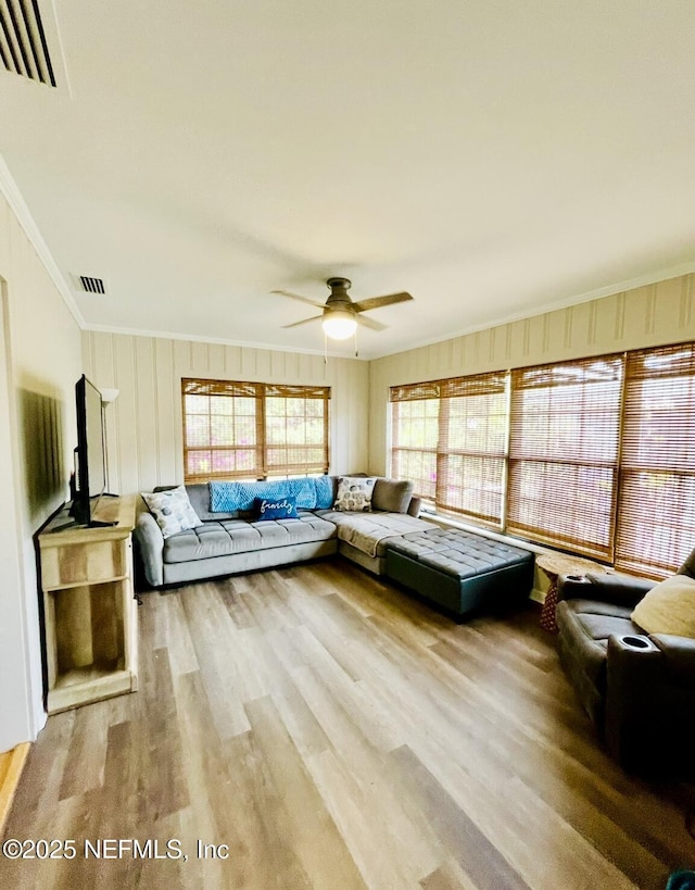 living area featuring ceiling fan, wood finished floors, visible vents, and crown molding