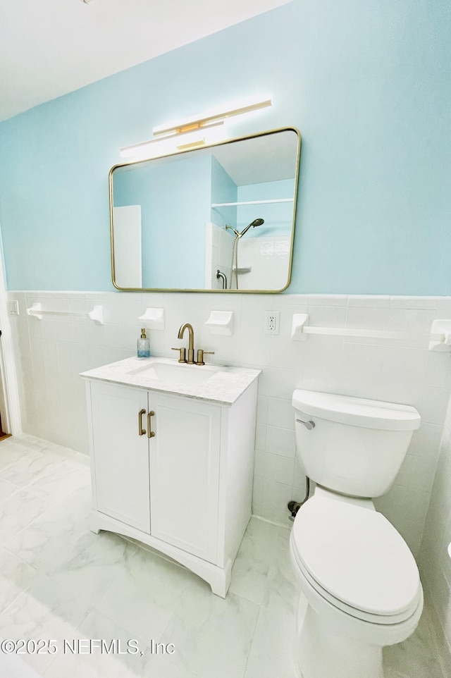 bathroom featuring marble finish floor, wainscoting, vanity, and toilet