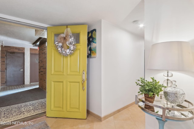 entrance foyer with brick wall, baseboards, and light tile patterned floors