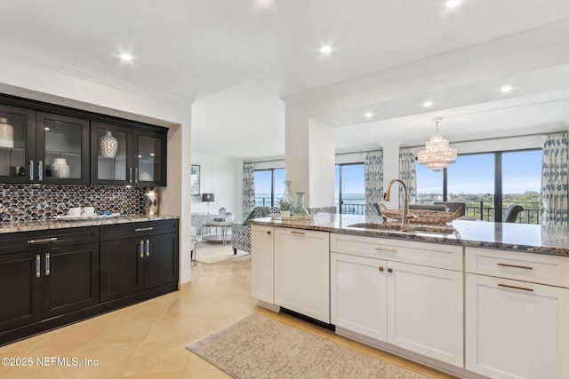 kitchen with paneled dishwasher, glass insert cabinets, white cabinetry, a sink, and light stone countertops