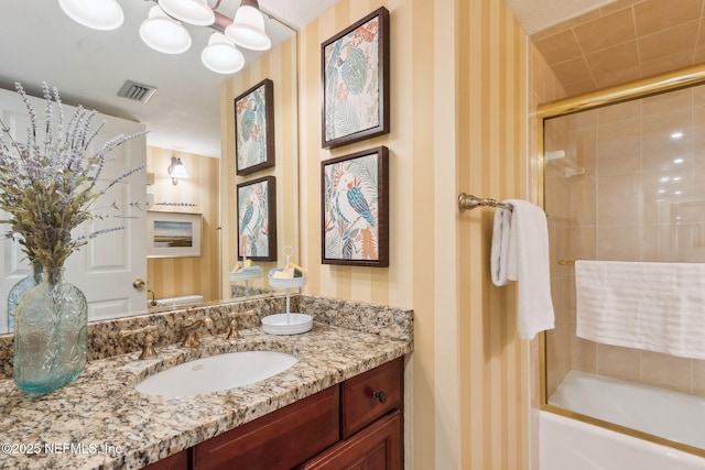 bathroom featuring wallpapered walls, visible vents, combined bath / shower with glass door, and vanity