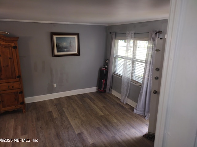 spare room with baseboards, crown molding, and wood finished floors