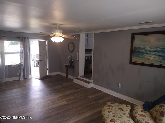 interior space with dark wood-type flooring, baseboards, ornamental molding, and ceiling fan