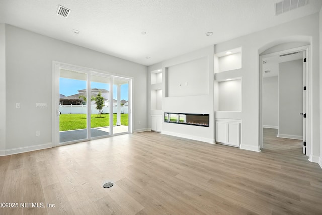 41 Iris Creek Dr, Saint Augustine, FL 32092 - unfurnished living room featuring light wood-style floors, a glass covered fireplace, and arched walkways