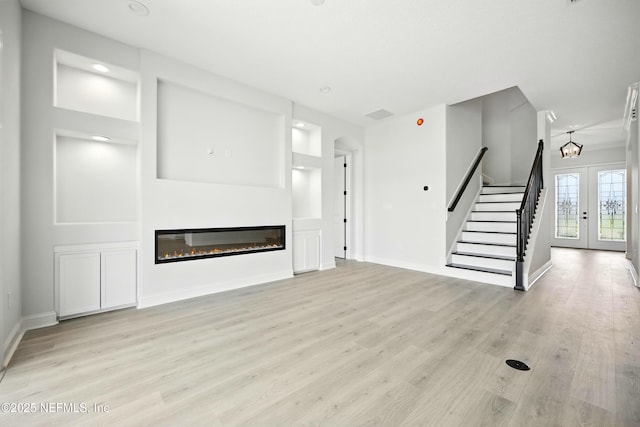 41 Iris Creek Dr, Saint Augustine, FL 32092 - unfurnished living room with stairs, light wood-type flooring, a glass covered fireplace, recessed lighting, and a chandelier