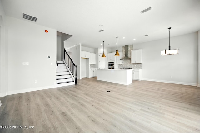 41 Iris Creek Dr, Saint Augustine, FL 32092 - unfurnished living room featuring light wood-style floors, recessed lighting, stairs, and a chandelier