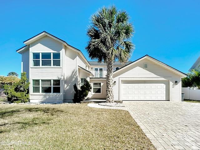 traditional-style home featuring decorative driveway, an attached garage, fence, and a front yard