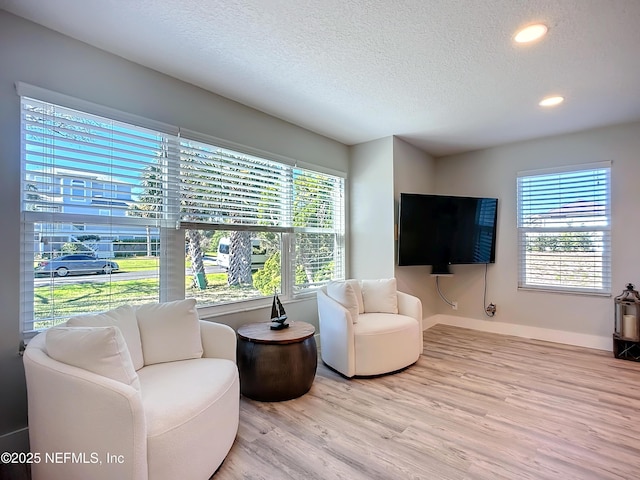 living room with a textured ceiling, recessed lighting, baseboards, and light wood-style floors