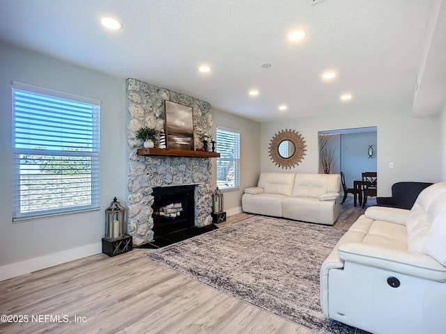 living room featuring light wood-style floors, recessed lighting, a fireplace, and baseboards