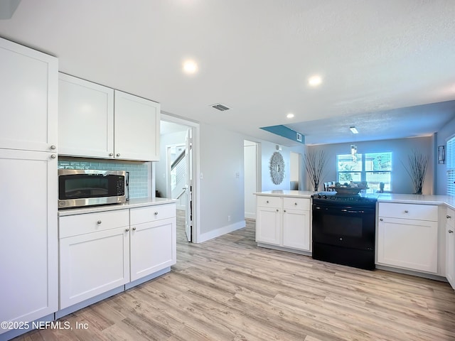 kitchen with visible vents, white cabinets, light wood-style flooring, stainless steel microwave, and black electric range oven