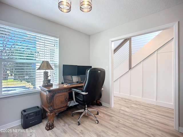 home office featuring baseboards, a textured ceiling, and light wood finished floors