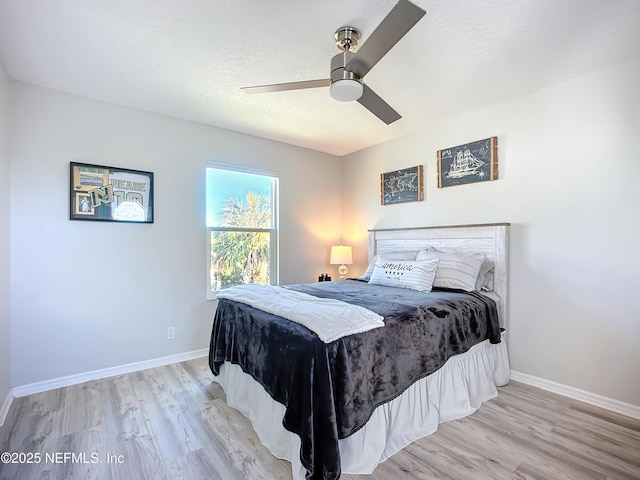 bedroom featuring a ceiling fan, a textured ceiling, baseboards, and wood finished floors