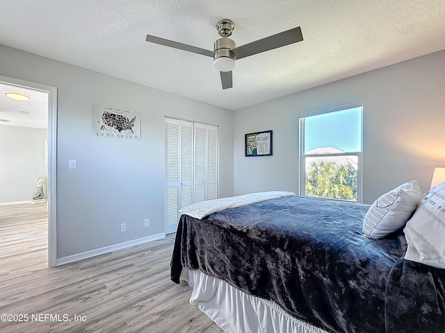 bedroom featuring baseboards, a ceiling fan, a textured ceiling, light wood-type flooring, and a closet