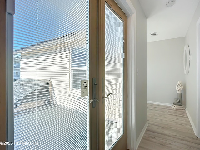 hall with french doors, visible vents, baseboards, and wood finished floors