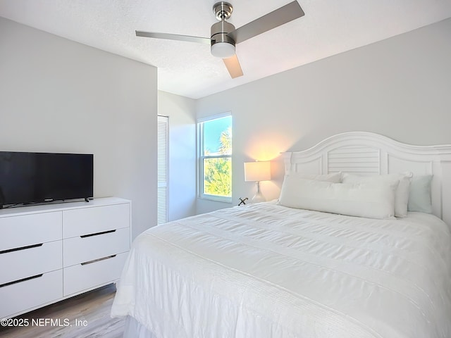 bedroom featuring ceiling fan, a textured ceiling, and wood finished floors