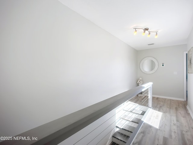 corridor featuring visible vents, light wood-style flooring, and baseboards