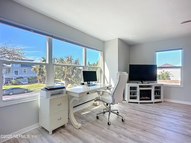 office area with light wood-type flooring, visible vents, a textured ceiling, and baseboards