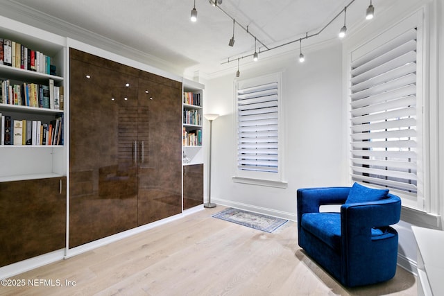 living area with baseboards, crown molding, track lighting, and wood finished floors