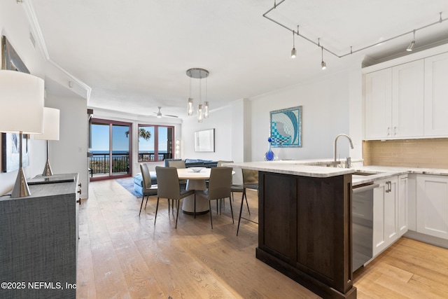 kitchen featuring open floor plan, stainless steel dishwasher, light wood finished floors, and white cabinets