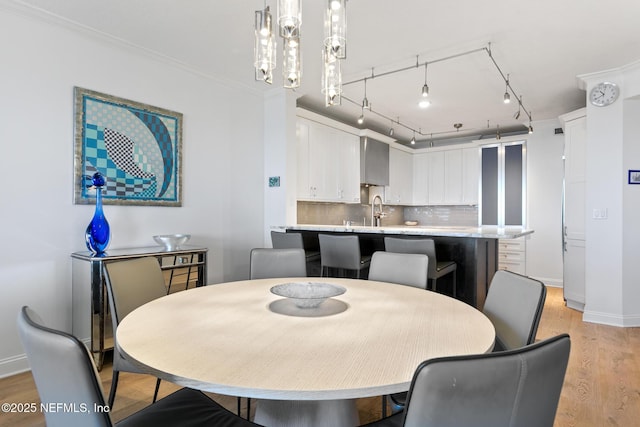 dining area featuring baseboards, light wood-style floors, an inviting chandelier, and crown molding