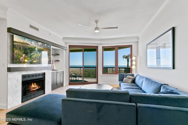 living room featuring ornamental molding, visible vents, a premium fireplace, and wood finished floors