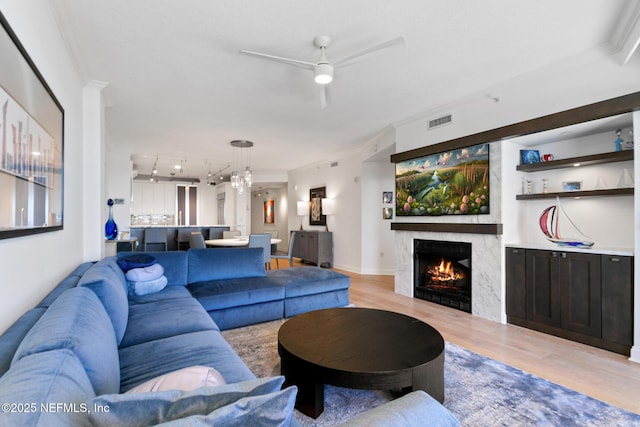 living room with light wood-style flooring, a fireplace, visible vents, and crown molding