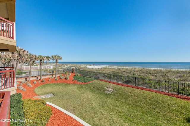 view of yard with a water view, fence, and a beach view