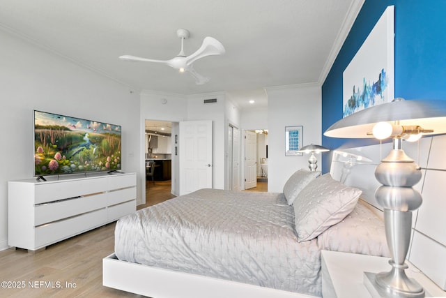 bedroom with ensuite bath, visible vents, crown molding, and wood finished floors