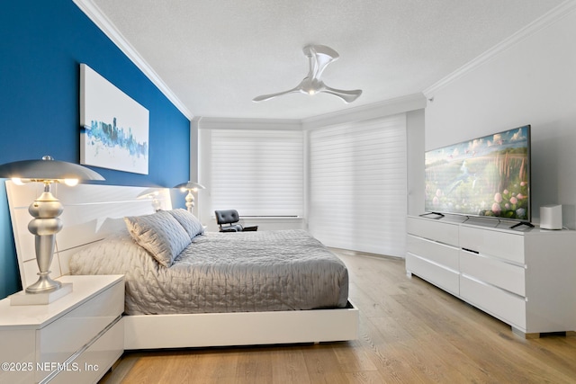 bedroom featuring ceiling fan, light wood finished floors, a textured ceiling, and crown molding