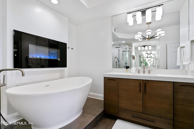 bathroom featuring vanity, a chandelier, a freestanding tub, baseboards, and walk in shower