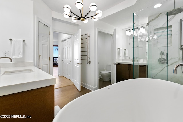 bathroom with a soaking tub, toilet, a shower stall, vanity, and baseboards