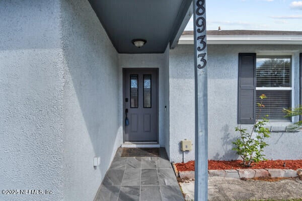 doorway to property featuring stucco siding