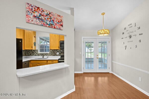 kitchen with a sink, light countertops, french doors, backsplash, and black appliances