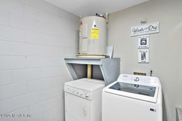 clothes washing area featuring laundry area, washing machine and dryer, and water heater