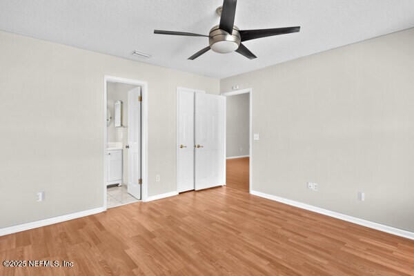 unfurnished bedroom with ensuite bath, light wood-style flooring, baseboards, and a ceiling fan