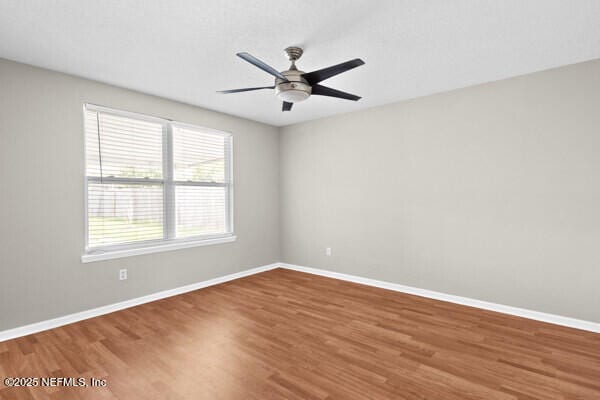 unfurnished room with ceiling fan, baseboards, and wood finished floors