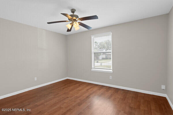 spare room featuring ceiling fan, wood finished floors, and baseboards