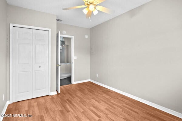 unfurnished bedroom with visible vents, baseboards, ceiling fan, wood finished floors, and a closet