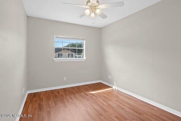 empty room with ceiling fan, baseboards, and wood finished floors