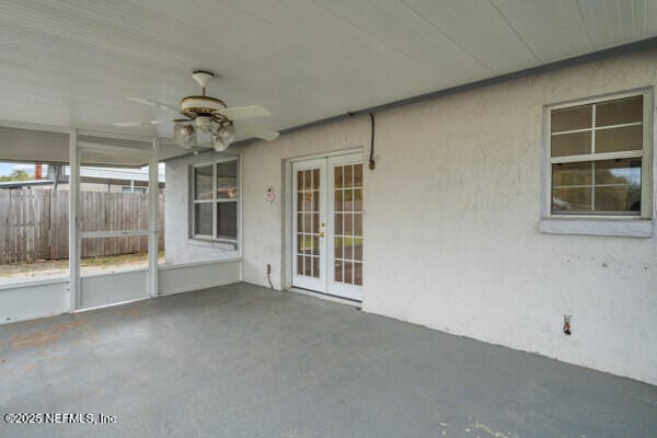 unfurnished sunroom featuring a ceiling fan and french doors