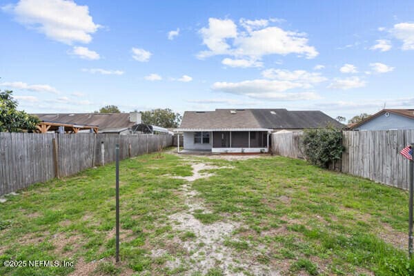 back of house with a sunroom, a fenced backyard, and a lawn