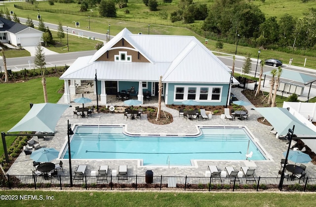 back of property featuring a patio area, a community pool, fence, and metal roof