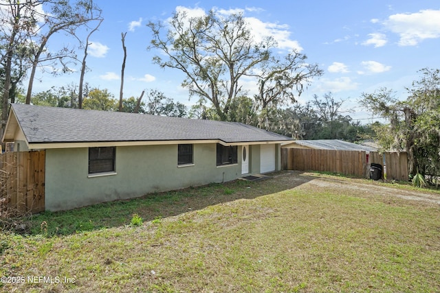 back of property featuring a yard, stucco siding, a shingled roof, fence, and driveway