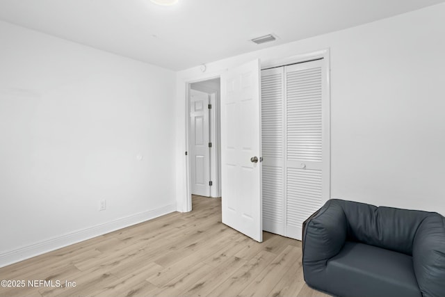 sitting room featuring light wood-style floors, visible vents, and baseboards