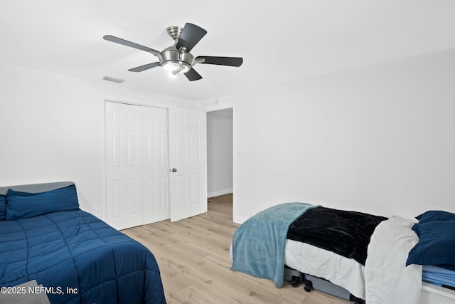 bedroom featuring ceiling fan, visible vents, baseboards, a closet, and light wood finished floors