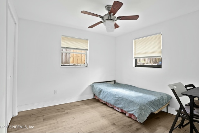 bedroom featuring a ceiling fan, baseboards, and wood finished floors