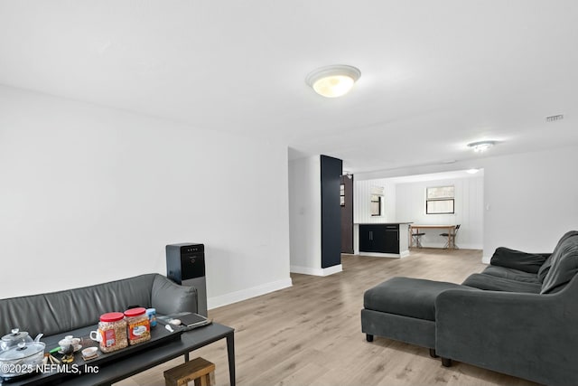 living area featuring light wood-type flooring, visible vents, and baseboards