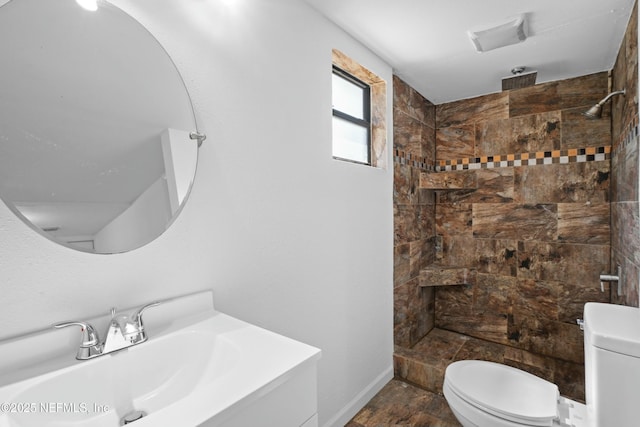 full bathroom with baseboards, a tile shower, vanity, and toilet