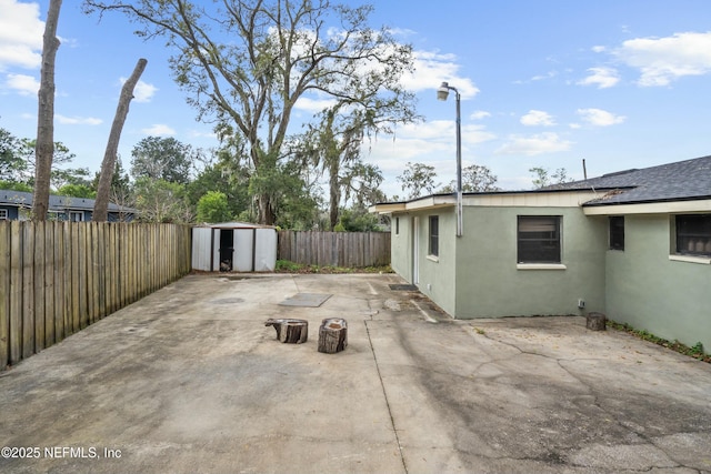 view of patio / terrace with a storage shed, a fenced backyard, and an outbuilding